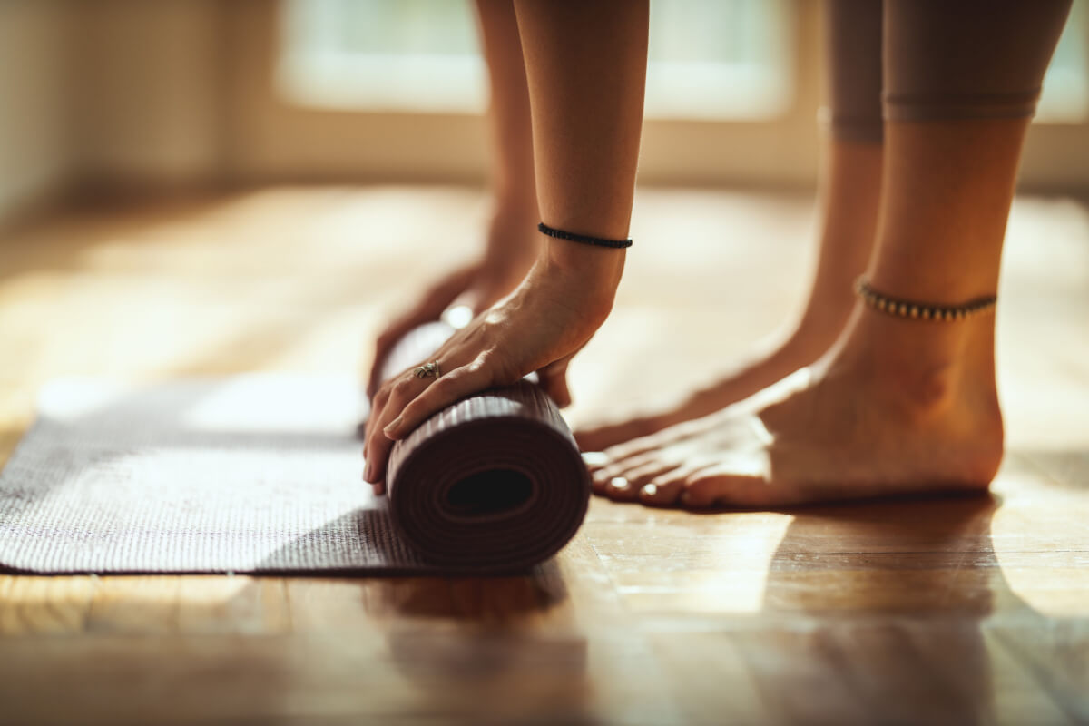 close up woman rolling yoga mat