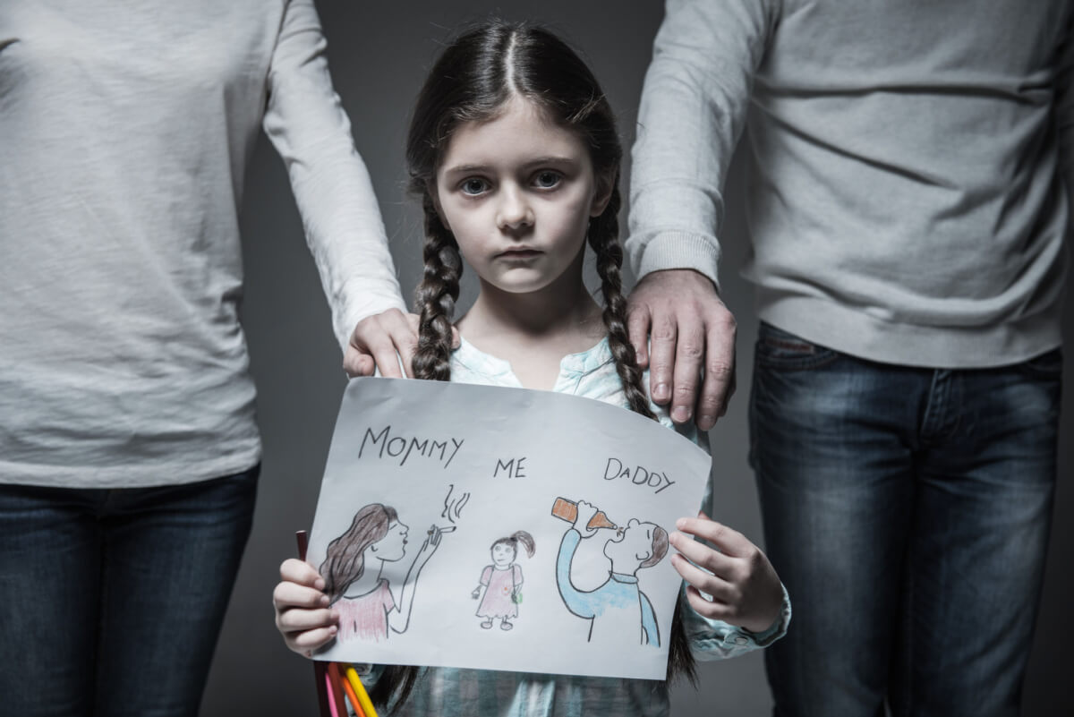 girl standing between parents with drawing