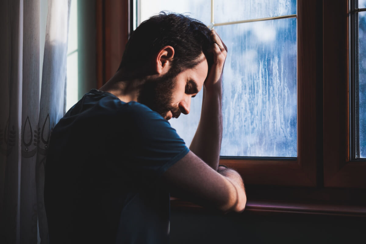 distraught man standing by window