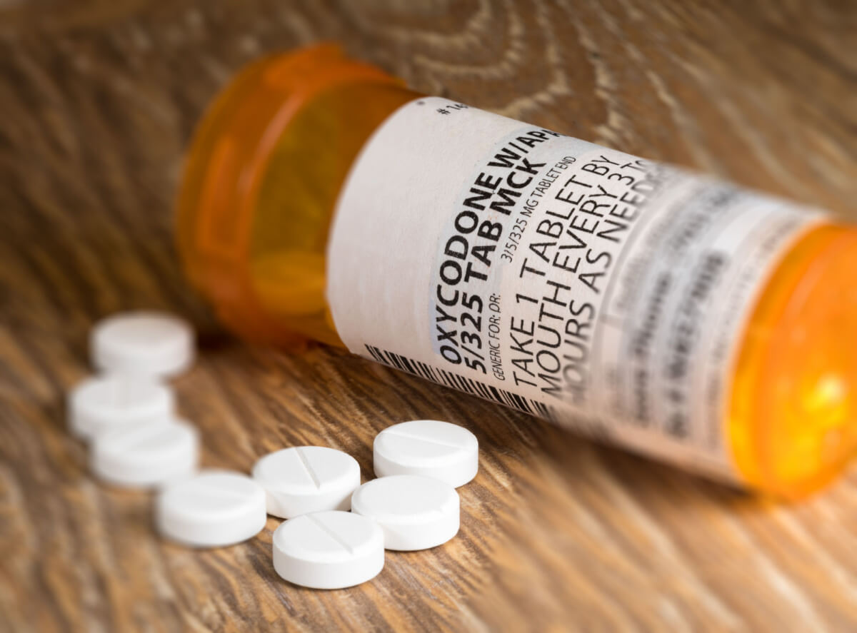 Oxycodone pills on wooden table with bottle