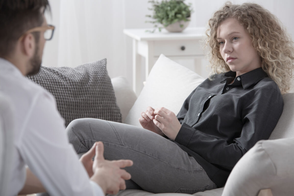 Young woman on couch listening to male psychologist